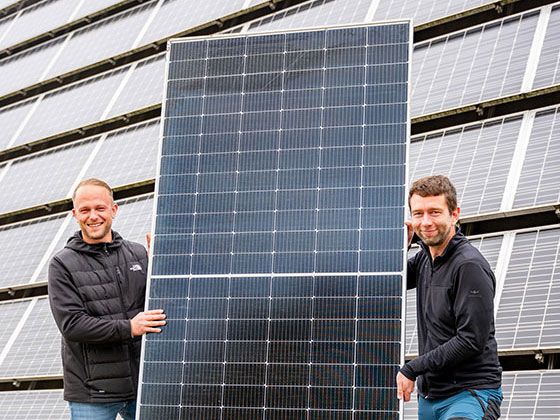 Christopher Kühnel und Paul Seefeld (beide Projektleiter PV) halten eines von vielen PV-Modulen, die für die neuen Photovoltaikanlagen verbaut wurden. Foto: Torsten Stapel
