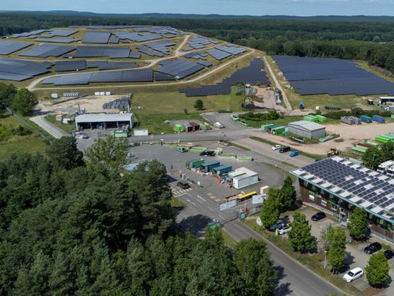 Luftaufnahme des Verwaltungs- und Entsorgungsstandort der Kreiswerke Barnim in Eberswalde Ostender Höhen am Waldrand mit großflächigen Solaranlagen auf einem Deponieberg, weiteren Photovoltaikfeldern, Betriebsgebäuden, Zufahrtsstraßen und abgestellten Fahrzeugen. (Foto: Torsten Stapel)