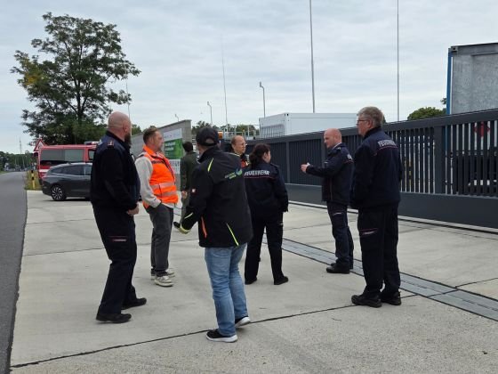 Vor der Wasserstofftankstelle in Basdorf für die Züge der NEB steht eine Gruppe aus Einsatzkräften sowie Mitarbeitenden der Kreiswerke und der NEB. Die Personen tragen überwiegend dunkle Einsatz- und Arbeitskleidung. Eine Person trägt eine Warnweste.(Foto: Anna-Lena Domes / Kreiswerke Barnim)