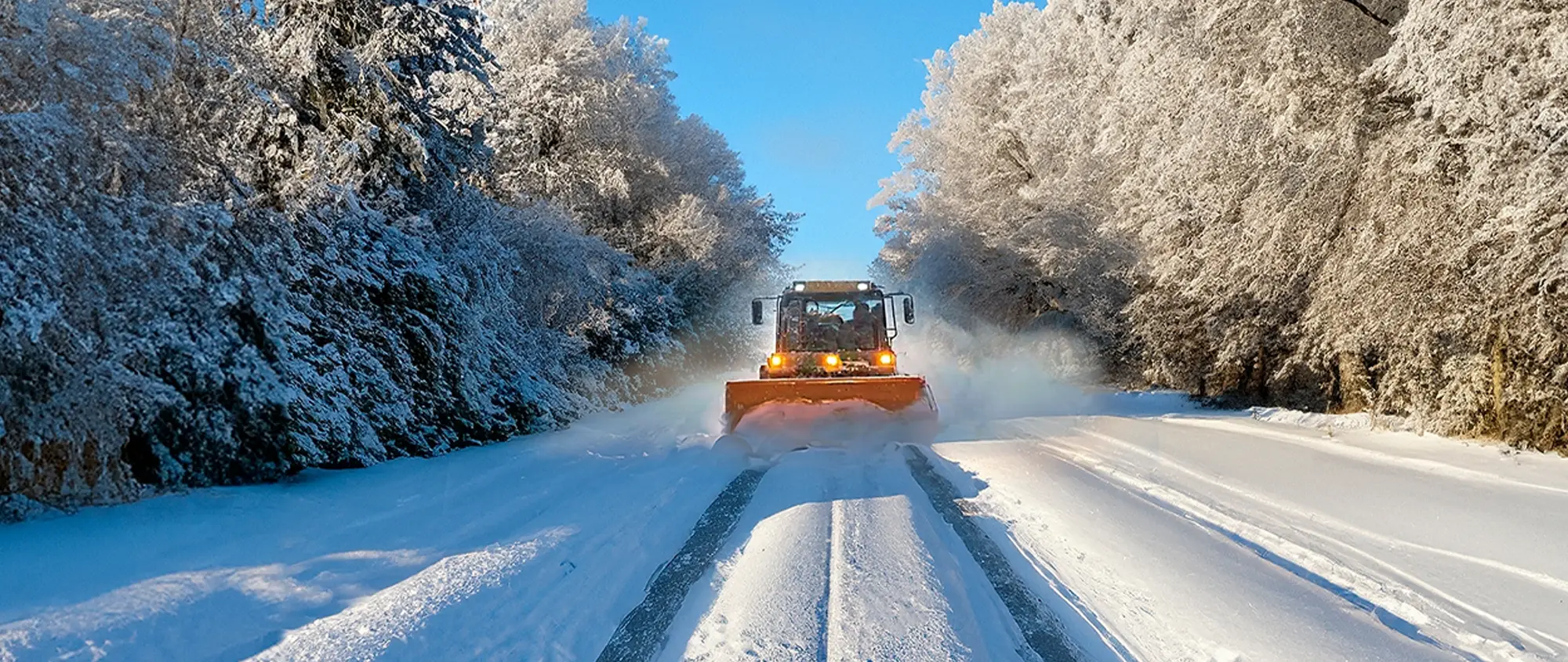 Räumfahrzeug der KIS im Winterdienst auf einer verschneiten Kreisstraße