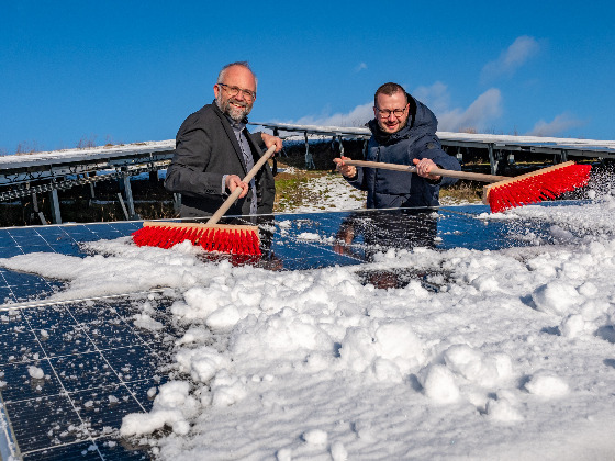 Landrat Daniel Kurth (li.) und Christian Mehnert, Geschäftsführer der Kreiswerke Barnim, beseitigen den Schnee von der PV-Anlage auf der Deponie Eberswalde.